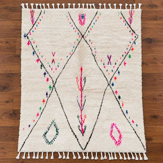 Full view of handmade Moroccan ivory and pink Berber wool rug on warm walnut wood floor